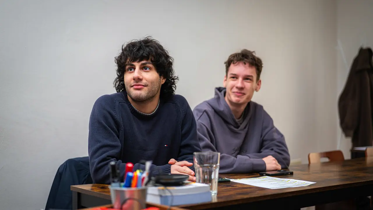 Two young business partners sitting side by side at a meeting table