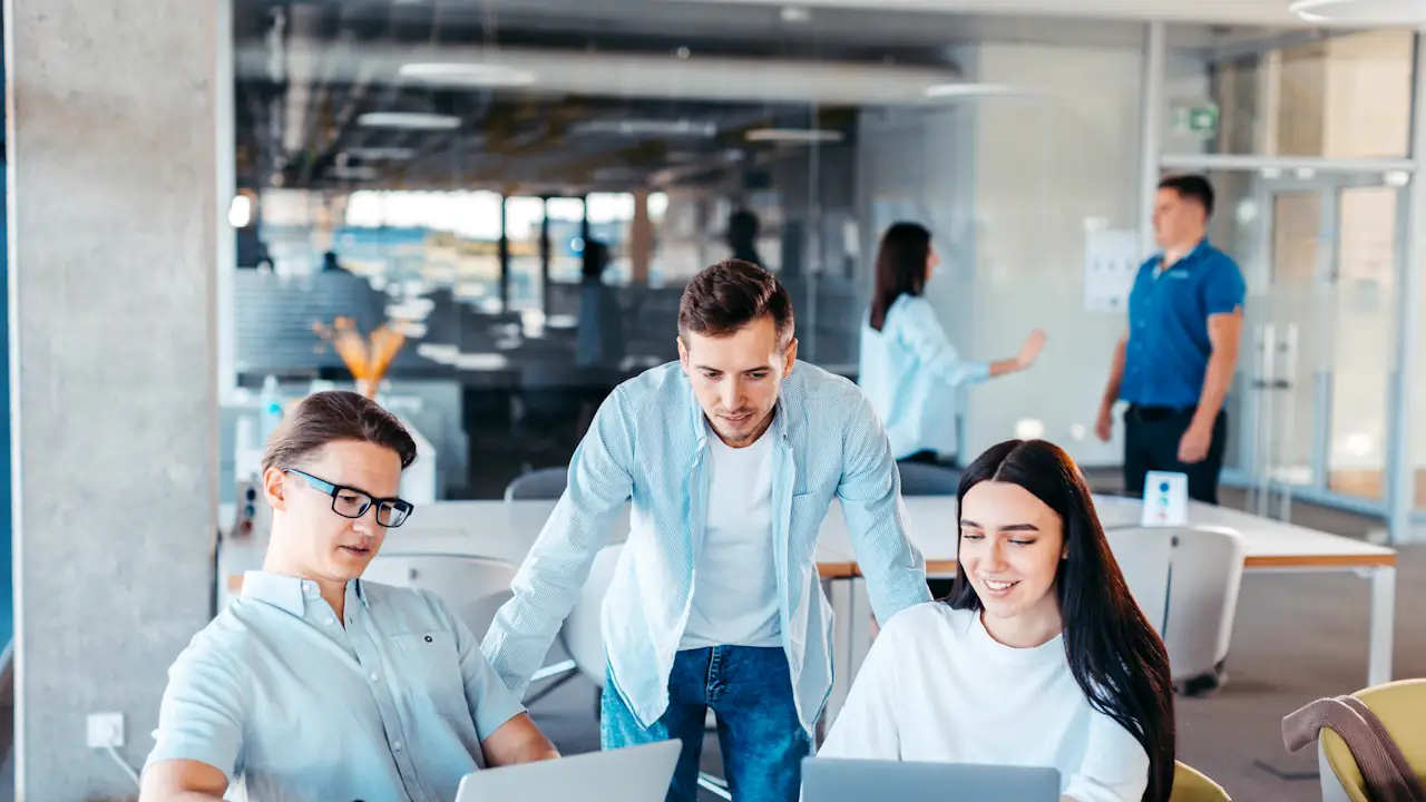 Three young colleagues working together at laptops in an open office