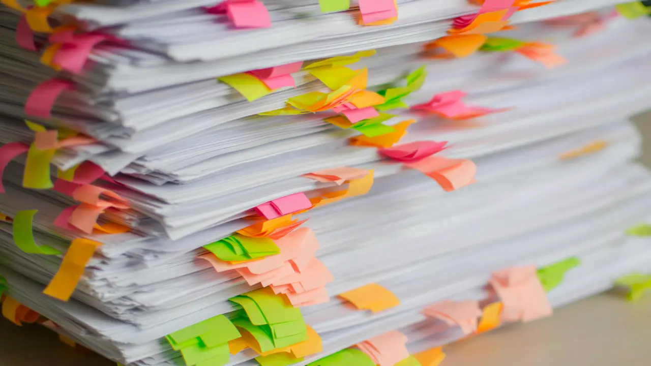 A tall stack of papers marked with colourful sticky tabs